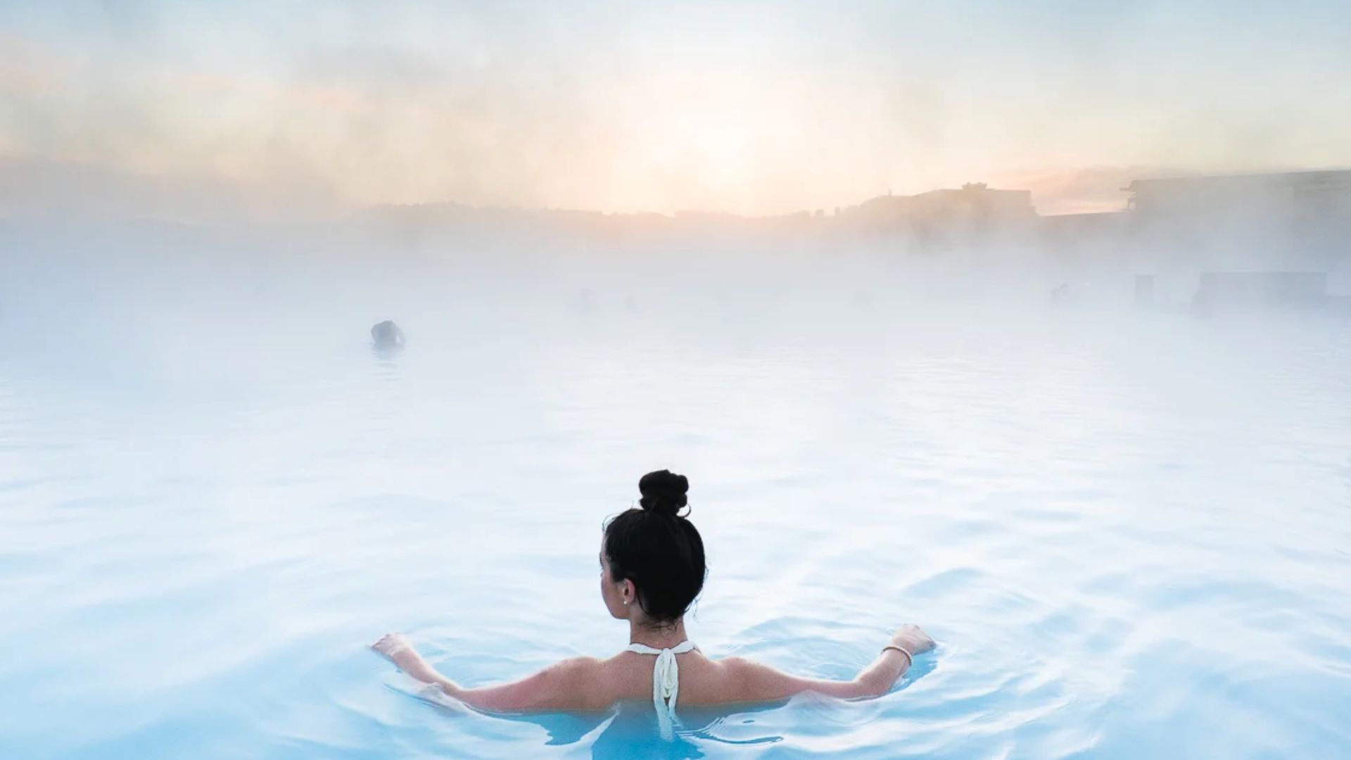 A woman relaxing in the steaming milky blue water of a geothermal lagoon in Iceland